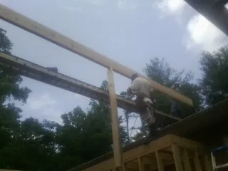 Carpenter setting a ridge beam over a new addition frame — Ice Dam Removal by Roofing Brothers in Naturita