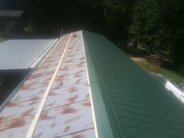 Old rusted panels beside newly installed green metal roofing — Wind Damage Roof Repair by Roofing Brothers in Naturita