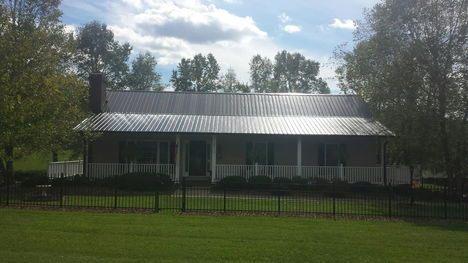 Gray metal roof on a brick ranch with a full width front porch — Gutter Guard Installation work by our crew in Naturita