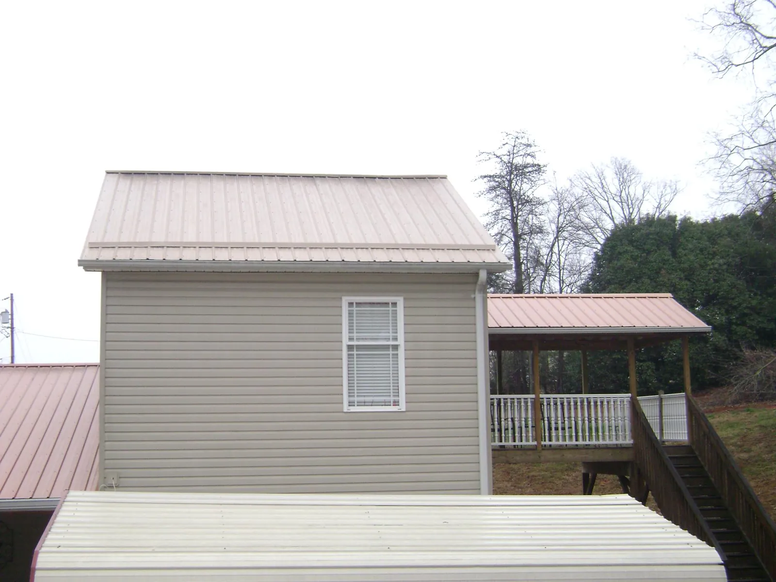 Tan metal roofs on a two story addition and attached porch, from a Roof Replacement job in Naturita